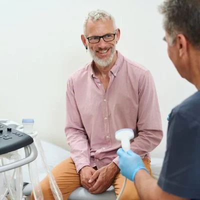 gray haired man in an ultrasound room communicates