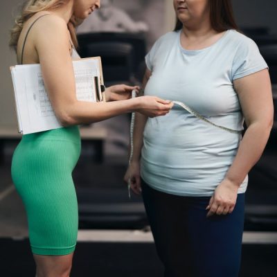 Female caucasian instruction checking the measuring of woman